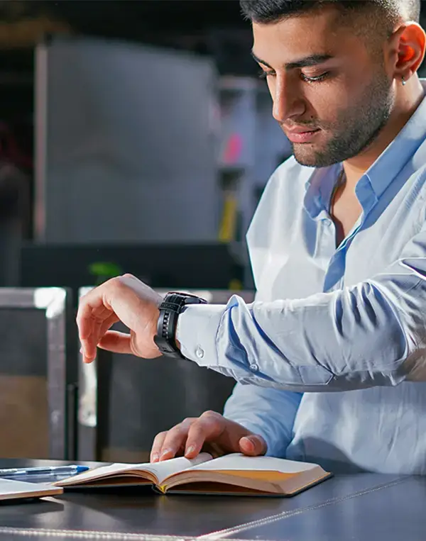 Man checking watch while taking notes of how long every task takes